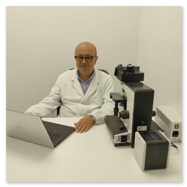 Il Professor Alfonso Baldi medico chirurgo specializzato in anatomia patologica alla scrivania davanti al computer e al microscopio