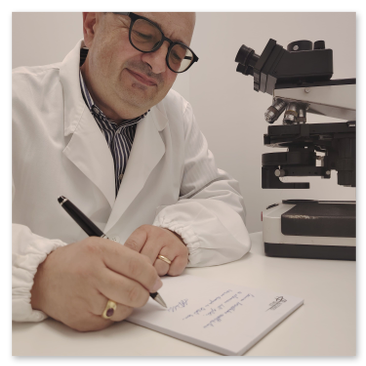 Il Professor Alfonso Baldi seduto alla sua scrivania mentre redige un referto istologico
