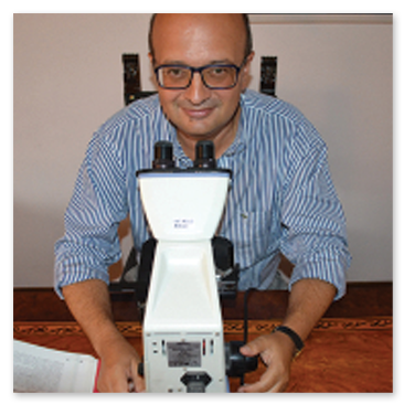 Foto storica del Professor Alfonso Baldi in studio con il microscopio professionale.
